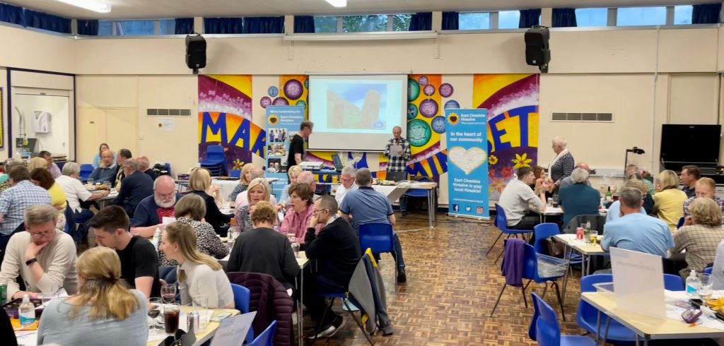 Photo of lots of people sat around tables in teams taking part in a Hospice quiz.
