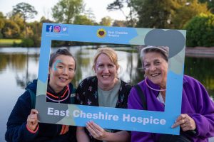 Photo of three Starlight Walk participants posing inside a large frame with East Cheshire Hospice branding