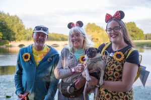 Photo of three Starlight Walk participants and a dog waring sunflowers and headgear.