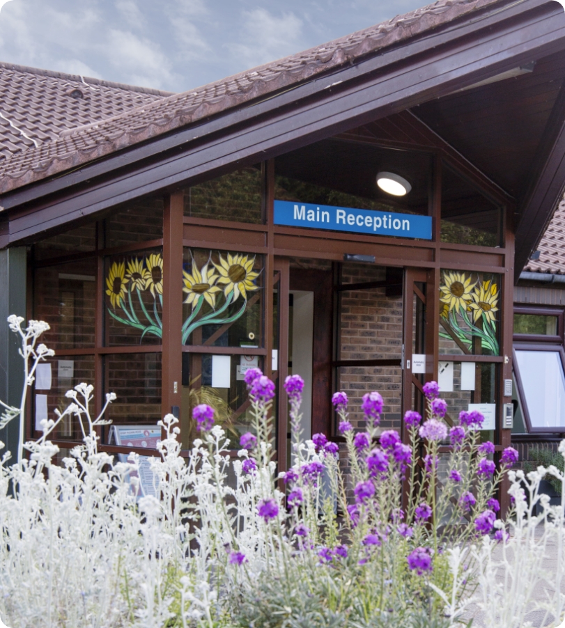 Photo of the front of the Hospice entrance with colourful shrubbery in the foreground