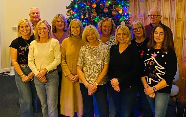 A group photo of Hospice Befrienders stood in the Hospice Chapel looking at the camera
