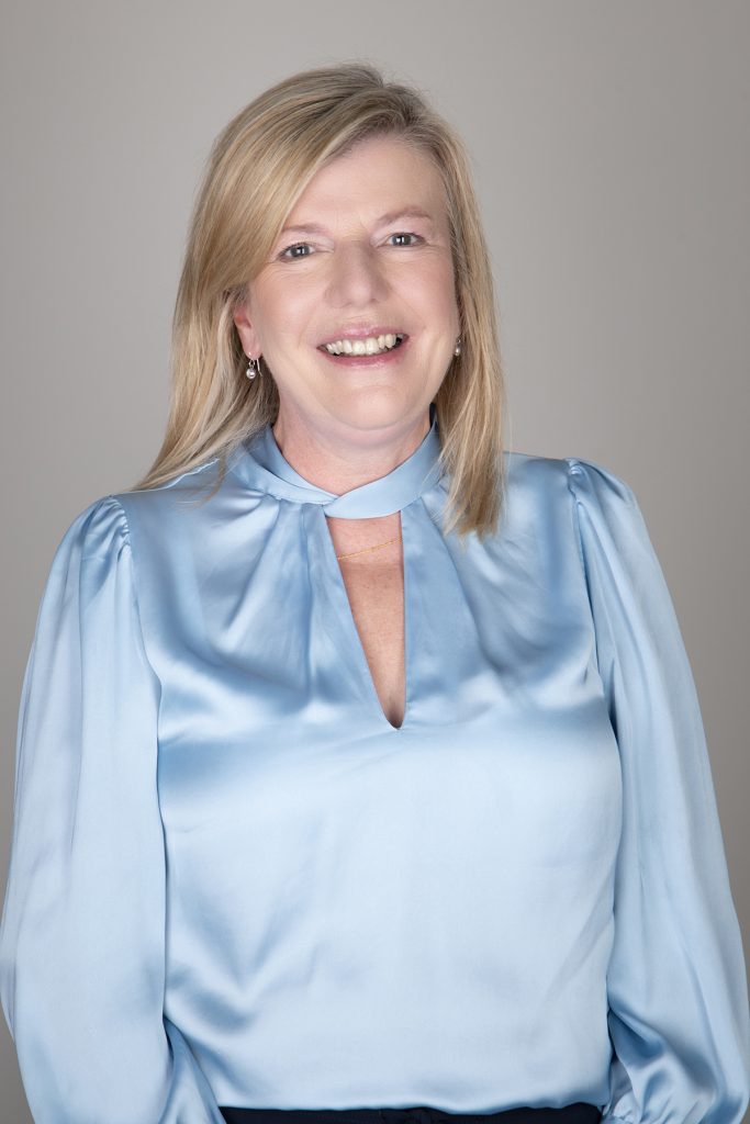 Philanthropy Manager April Green smiling at the camera against a grey backdrop