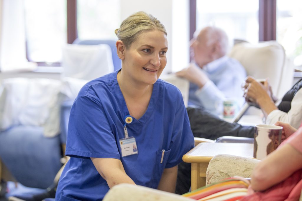 Nurse in blue uniform smiles while tending to patient in Sunflower Centre