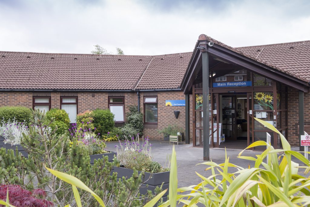 Photo of the front of the Hospice with greenery and plants in the foreground