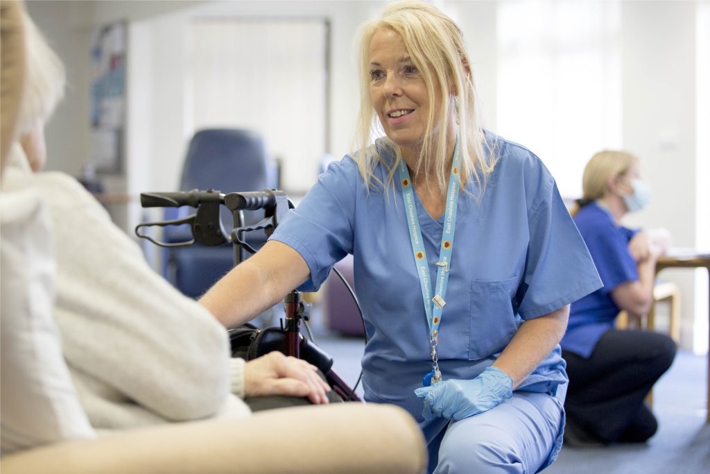 Nurse in blue uniform smiling in front of patient