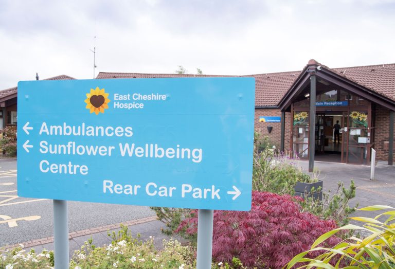 Photo of a blue sign in front of the Hospice with directions to different areas for drivers.