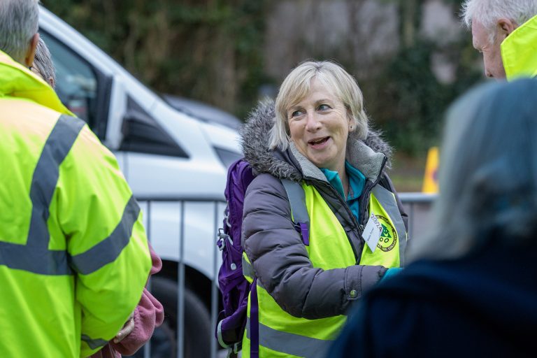 A lady with a high vis jacket on is smiling with other people