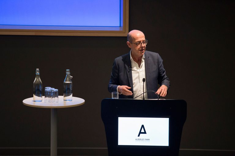 A man is stood up with a microphone making a speech