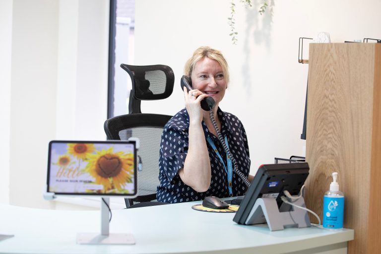 Lady sat at her desk smiling whilst on the phone