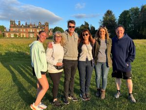 Photo of group of 6 participants smiling at the camera on grass in front of Capesthorne Hall