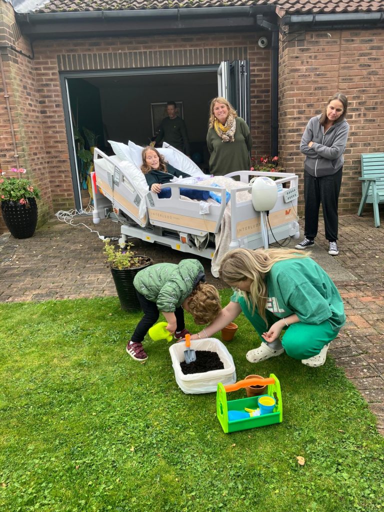 Elaine and her family at the Hospice in the Hospice gardens planting a plant with children's toys.