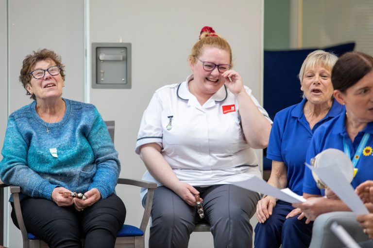 Photo of a patient sat with several Sunflower Living Well Centre staff laughing together.