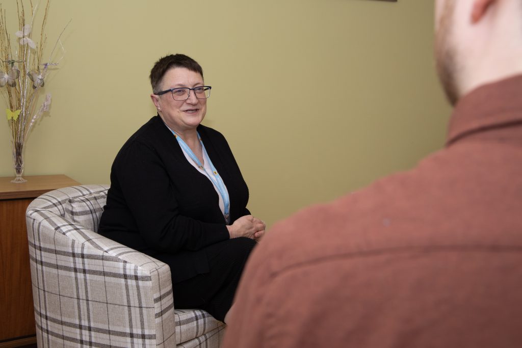 Photo of Hospice Chaplain Marion sitting having a conversation with someone