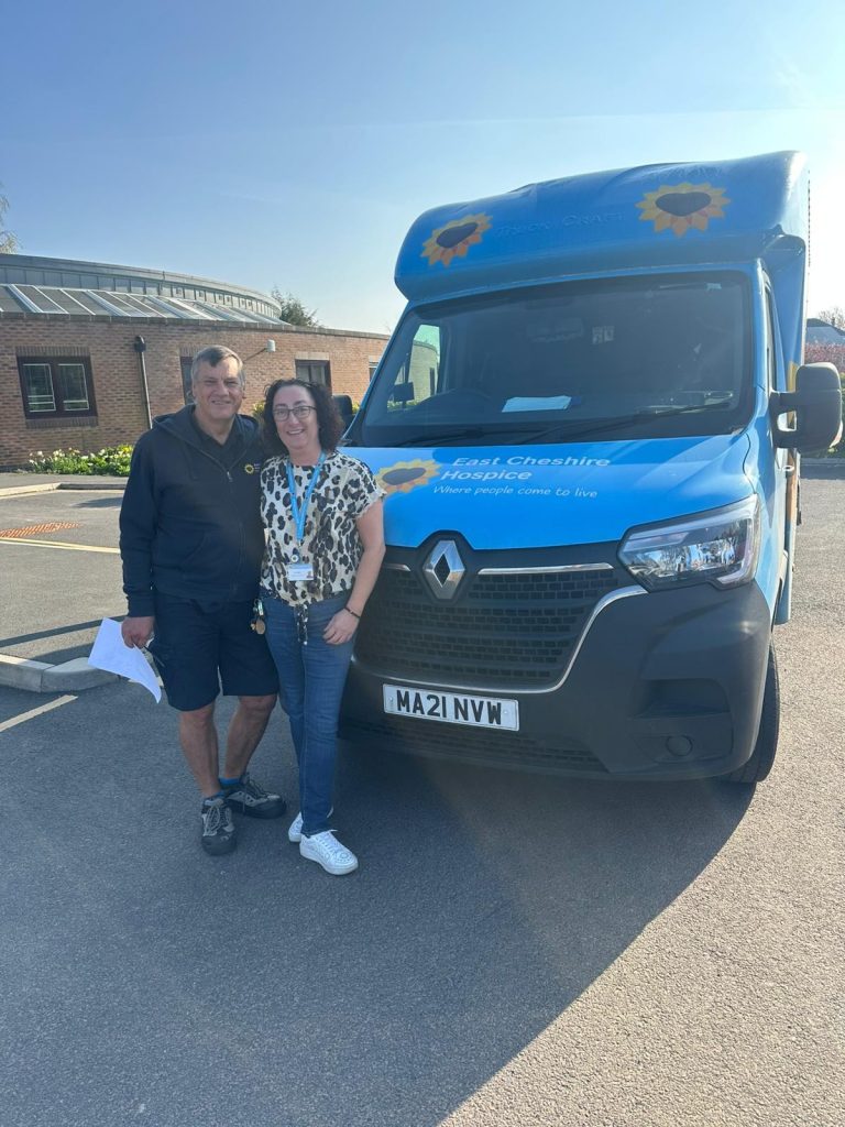 Photo of Toni and John stood by the Hospice van looking at the camera.