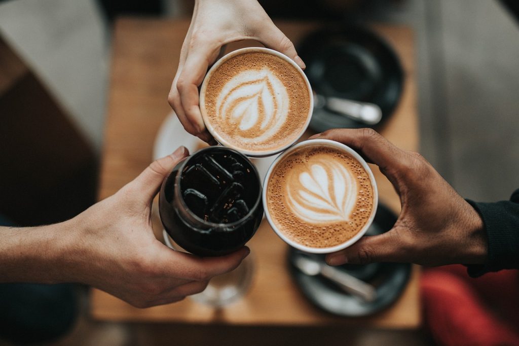 Photo of three people's hands holding coffee cups together