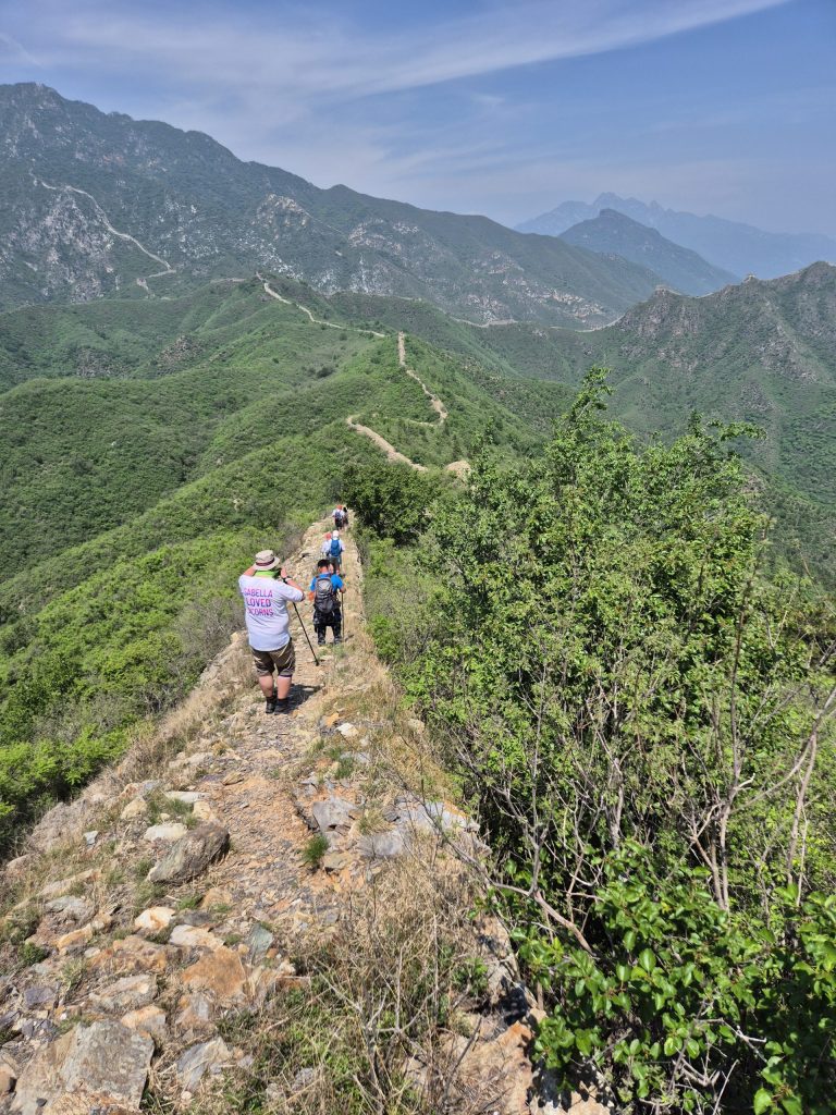 Photo of people walking away along the Great Wall of China with the rural landscape in the background