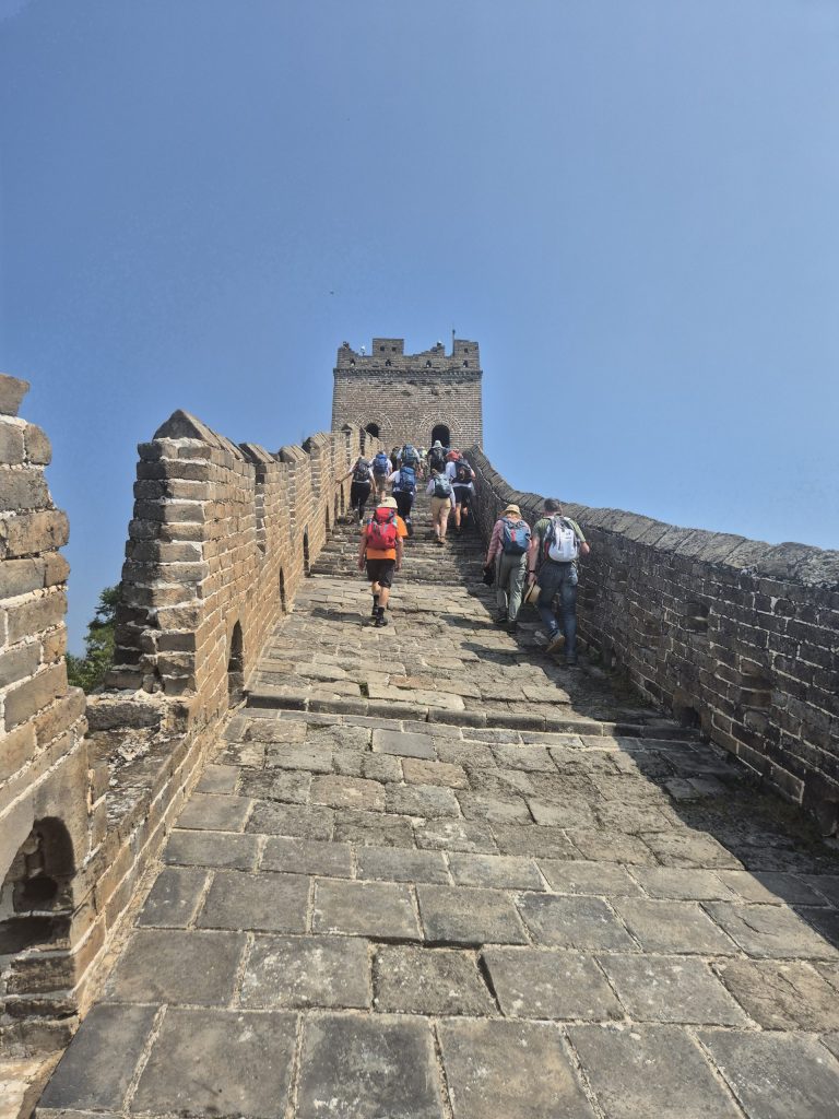 Photo of people walking away along the Great Wall of China with the rural landscape in the background