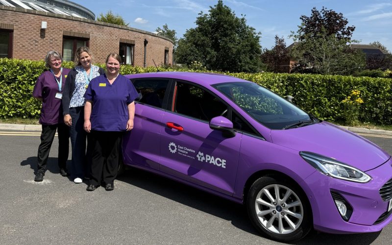 Phot of three Hospice staff standing next to a purple car with PACE branding on it.