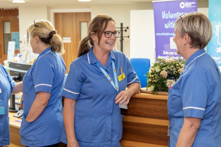 Photo of a group of nurses chatting together in front of the Hospice reception.