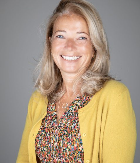 A portrait photograph of a lady smiling at the camera