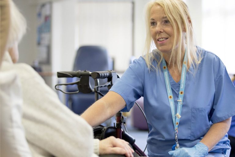 Nurse in blue uniform smiling in front of patient