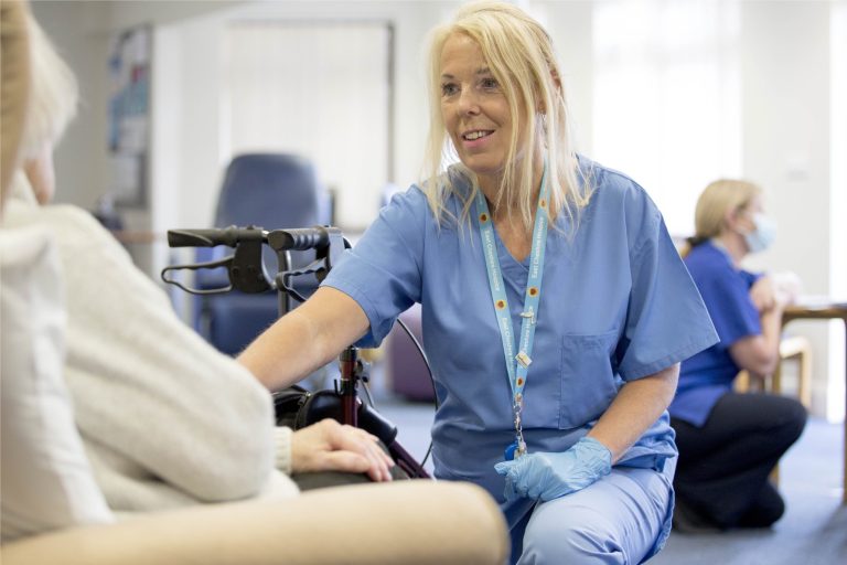 Nurse in blue uniform smiling in front of patient