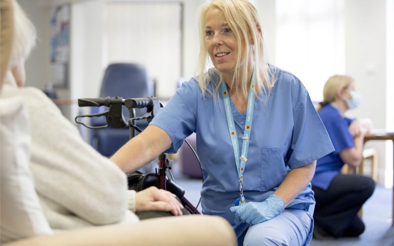 Nurse in blue uniform smiling in front of patient