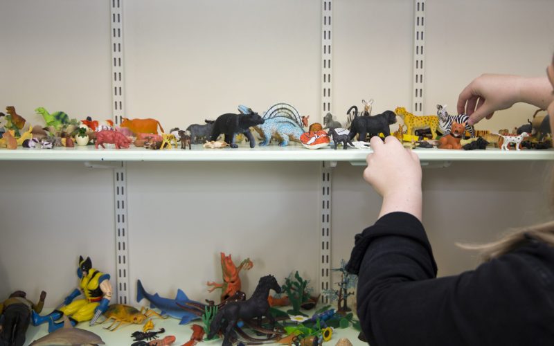 Child playing with variety of children's toys on a shelf in East Cheshire Hospice's Child's Therapy room