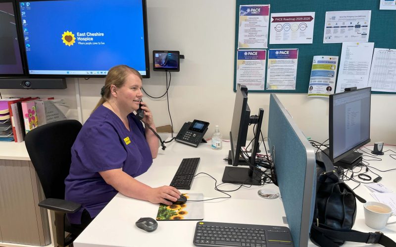 PACE staff member in purple uniform speaking on the phone and looking at a computer screen.