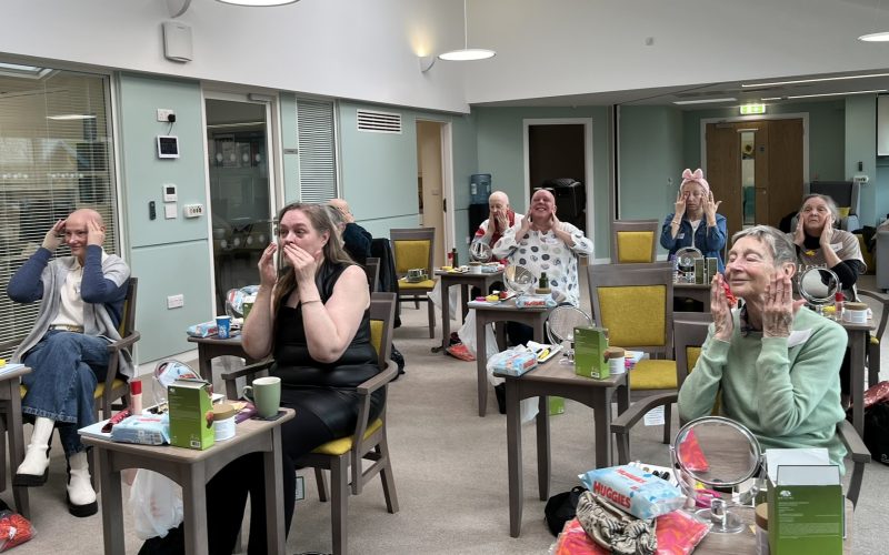 Photo of a group of Look Good Feel Better group participants sitting in the Sunflower Living Well Centre enjoying applying beauty products from their goodie bags.