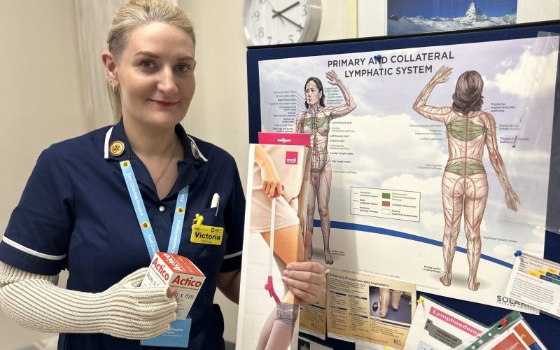 A nurse who works for the Hospice standing in front of a poster showing the lymphatic system