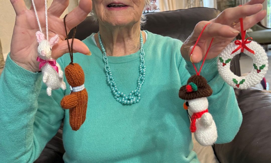 Handmade goods volunter, Betty Malkin sat in a chair with handmade items being shown to camera