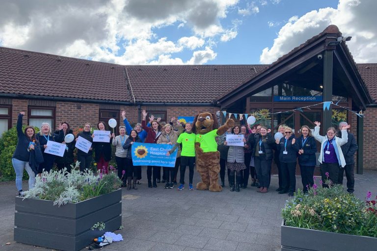 Group of East Cheshire Hospice supporters and staff members outside the front of the Hospice, cheering challenge supporter for his success