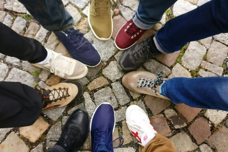 Nine pairs of shoes in a circle. Person with one foot forward to create the circle.