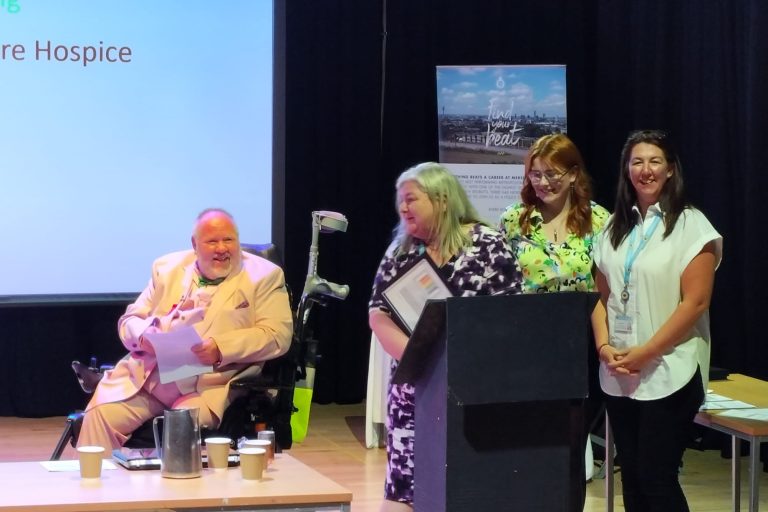 3 ladies standing and receiving an award on behalf of the Hospice