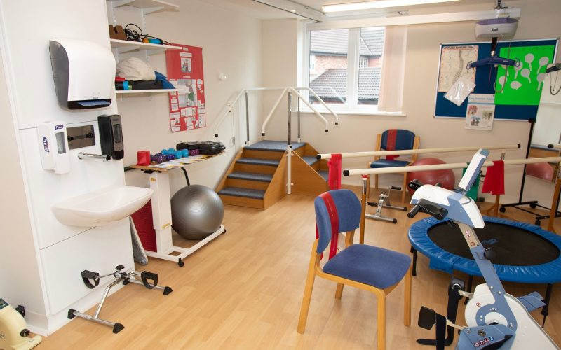 A photo of a physio room with a mini trampoline, yoga balls and physio stairs