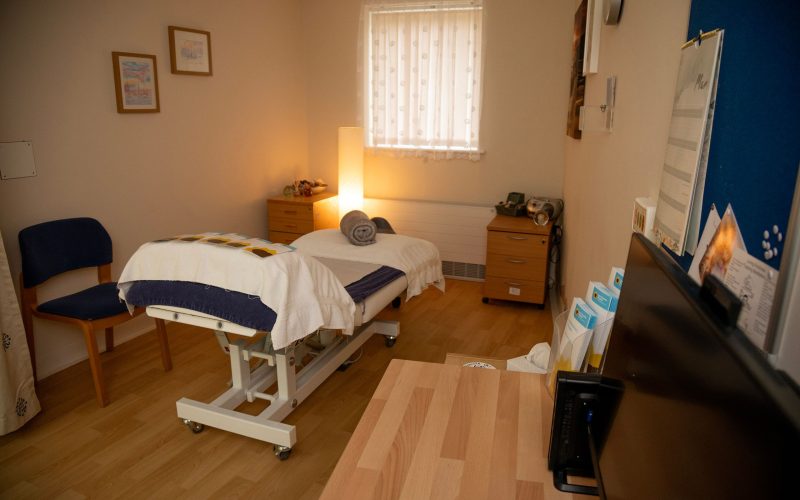 A single bed in the middle of one of the rooms in the Hospice with light shining in the corner of the room