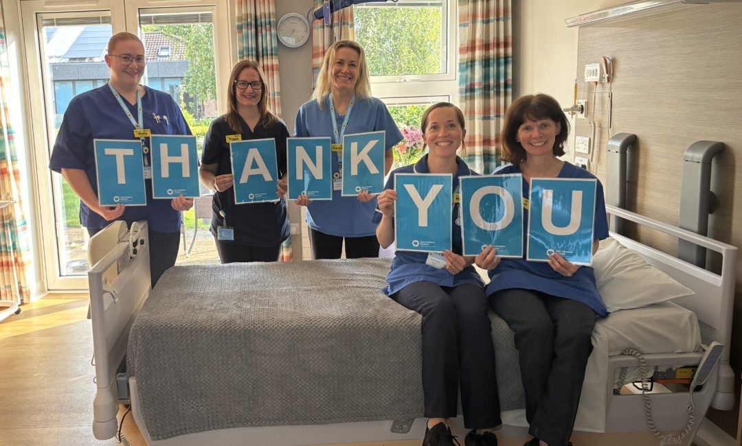Five nurses sat on a Hospice bed with the posters saying thank you.
